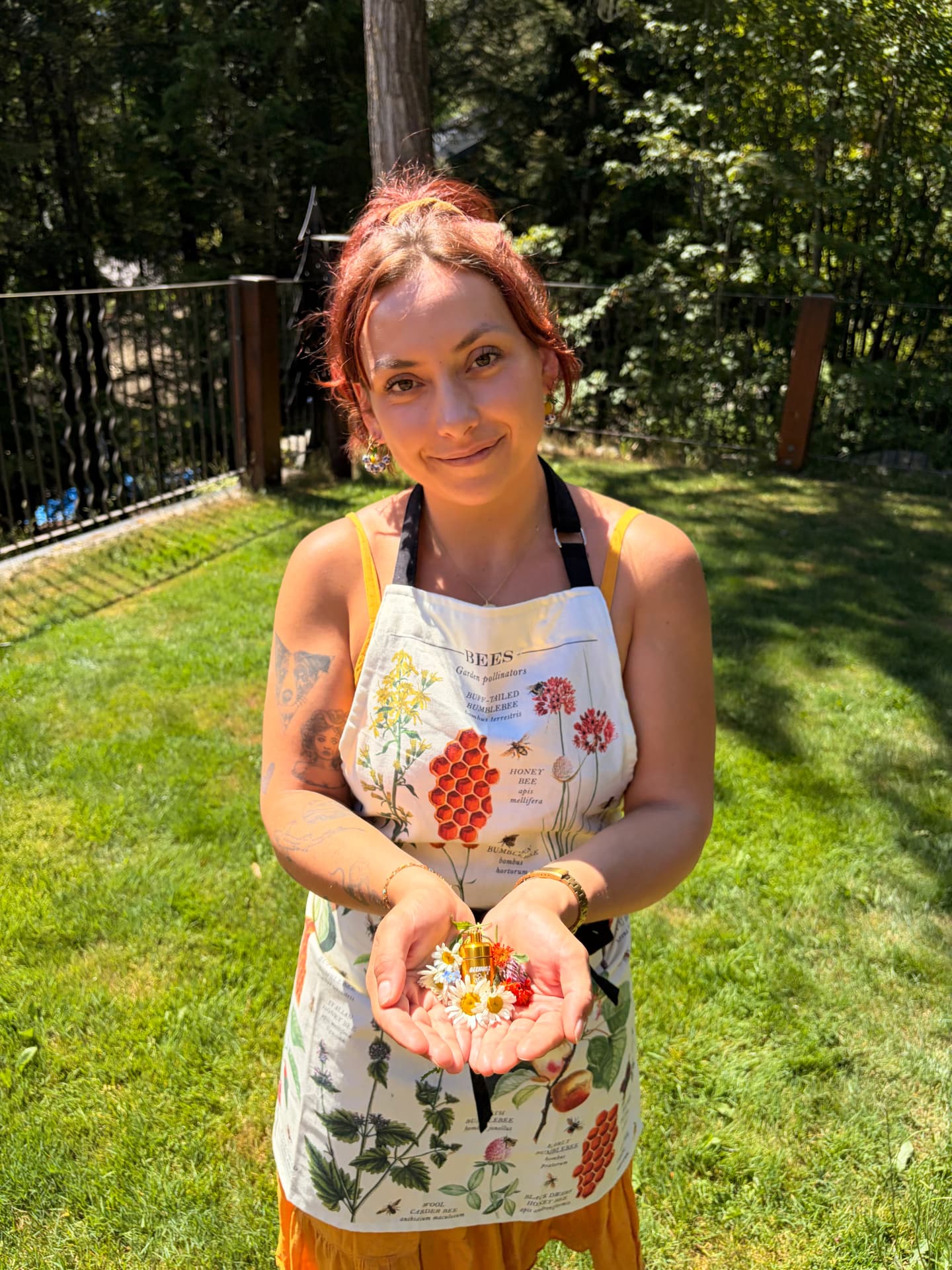 Belle, founder of Beehugz, wearing a botanical bee apron and holding fresh flowers